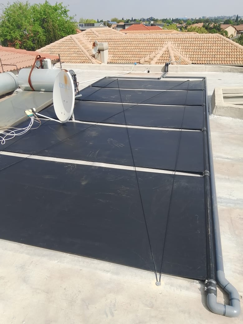 Close-up of solar pool heating panels with feed lines on a tiled roof